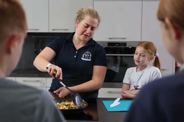 Eine Ern&auml;hrungsberaterin vermittelt Kindern beim Kochen in der praxiseigenen K&uuml;che spielerisch und praxisnah Wissen