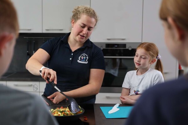 Eine Ern&auml;hrungsberaterin vermittelt Kindern beim Kochen in der praxiseigenen K&uuml;che spielerisch und praxisnah Wissen