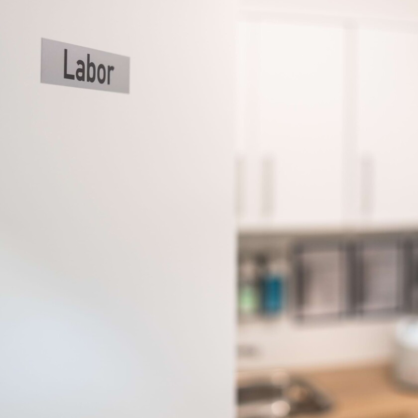 T&uuml;rschild mit Aufschrift &bdquo;Labor&ldquo; an einer wei&szlig;en Wand.