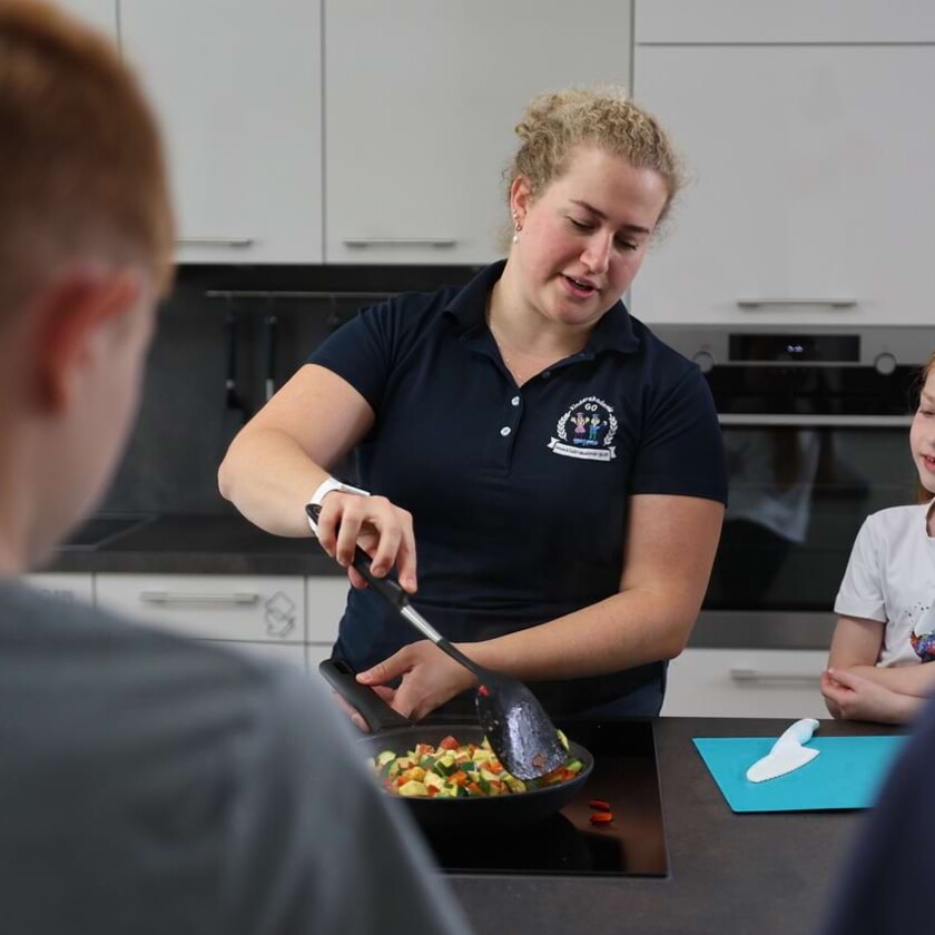 Eine Ern&auml;hrungsberaterin vermittelt Kindern beim Kochen in der praxiseigenen K&uuml;che spielerisch und praxisnah Wissen