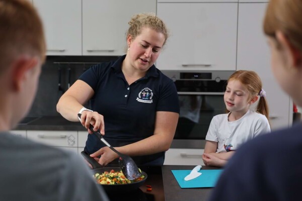 Eine Ern&auml;hrungsberaterin vermittelt Kindern beim Kochen in der praxiseigenen K&uuml;che spielerisch und praxisnah Wissen