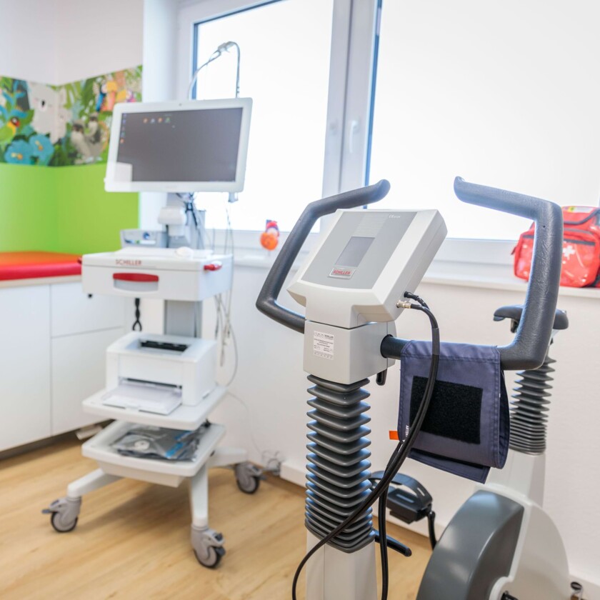 Medizinischer Ergometer und EKG-Ger&auml;t auf Rollwagen in heller Arztpraxis.