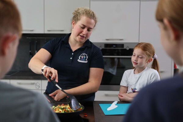 Eine Ern&auml;hrungsberaterin vermittelt Kindern beim Kochen in der praxiseigenen K&uuml;che spielerisch und praxisnah Wissen
