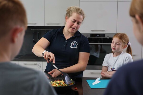Eine Ern&auml;hrungsberaterin vermittelt Kindern beim Kochen in der praxiseigenen K&uuml;che spielerisch und praxisnah Wissen